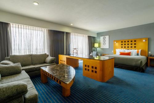 a hotel room with a couch and a bed at Real Inn Ciudad Juarez by the USA Consulate in Ciudad Juárez