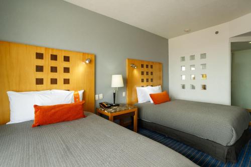 a hotel room with two beds with orange pillows at Real Inn Ciudad Juarez by the USA Consulate in Ciudad Juárez
