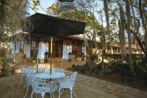 a table and chairs with an umbrella in front of a house at Hotel Finca Buenos Aires Barichara in Barichara