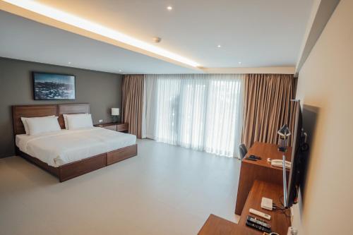 Solitude Acacia Resort في مابيني: غرفة نوم بسرير ومكتب وتلفزيون
