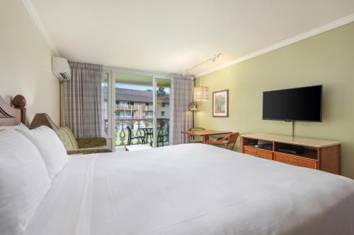 a bedroom with a white bed and a flat screen tv at Aston Islander On The Beach in Kapaa