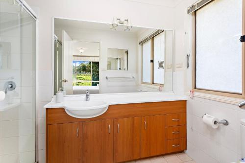 La salle de bains est pourvue d'un lavabo et d'un grand miroir. dans l'établissement Bella Vista, à Gerringong