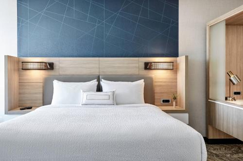 a bedroom with a white bed and a blue wall at SpringHill Suites by Marriott Oklahoma City Midwest City Del City in Del City