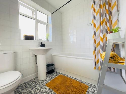 La salle de bains est pourvue d'un lavabo, de toilettes et d'une baignoire. dans l'établissement Central Luton 4 Bedroom home✪parking✪By Hostaguest, à Luton
