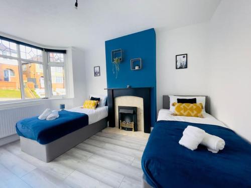 um quarto azul e branco com 2 camas e uma lareira em Central Luton 4 Bedroom home✪parking✪By Hostaguest em Luton