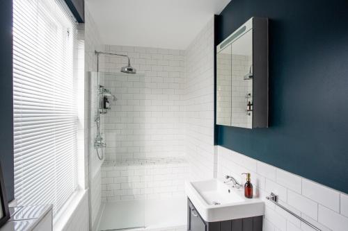 a white bathroom with a sink and a shower at Eden Grove - Islington - Studio Apartment in London