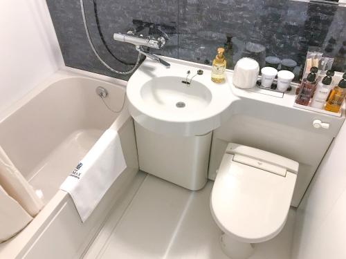 een kleine badkamer met een toilet en een wastafel bij HOTEL LiVEMAX BUDGET Iyo Mishima in Shikokuchuo