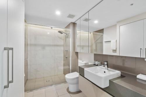 a bathroom with a toilet and a sink and a shower at Modern Riverside Oasis - Gym Pool WiFi & Parking in Brisbane