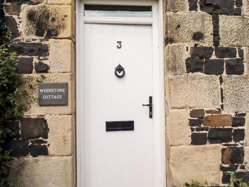 a white door in a brick building with a sign on it at Whinstone Bamburgh in Bamburgh