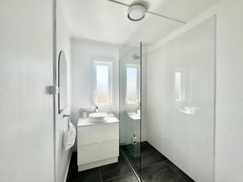 a white bathroom with a sink and a mirror at Townsville Suites in Townsville