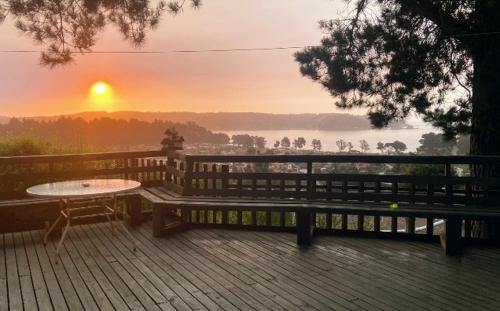 a bench on a deck with a table and a sunset at Pingueral in Dichato