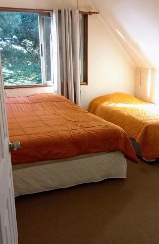 two beds in a room with a window at Pingueral in Dichato