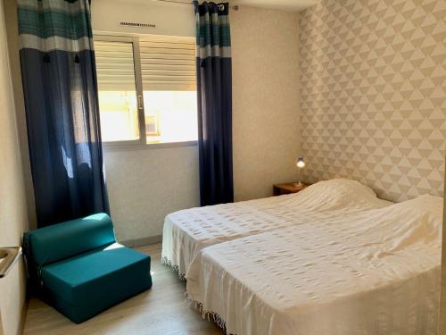 une chambre avec un lit et une chaise bleue dans l'établissement Appartement à 2 pas de la plage de Mèze, climatisé, parking gratuit, labelisé 2 clés CLEVACANCES - FR-1-604-40, à Mèze