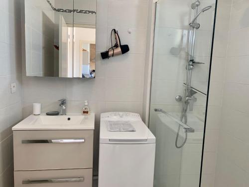 une salle de bain blanche avec une douche et un lavabo dans l'établissement Appartement à 2 pas de la plage de Mèze, climatisé, parking gratuit, labelisé 2 clés CLEVACANCES - FR-1-604-40, à Mèze