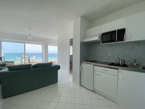 Il comprend un salon avec un canapé et une cuisine donnant sur l'océan. dans l'établissement Appartement avec terrasse, accès direct plage, parking privé - FR-1-368-396, à Trégastel