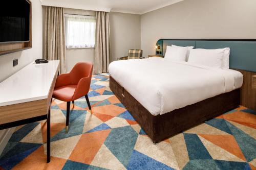 ein Hotelzimmer mit einem großen Bett und einem Stuhl in der Unterkunft Delta Hotels by Marriott Warwick in Warwick