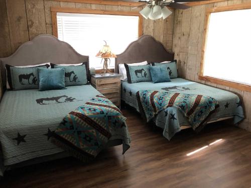 two beds in a bedroom with wooden walls and wood floors at Rockin' B Ranch Bluff House in Pipe Creek