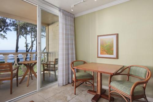 a dining room with a table and chairs and a balcony at Aston Islander On The Beach in Kapaa