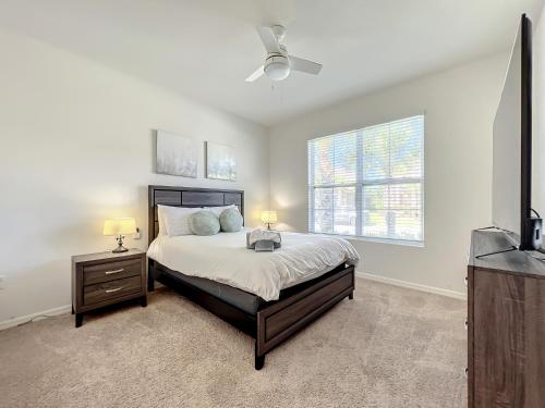a bedroom with a bed and two lamps and a television at 7 Bedroom 6 Bath Home with Private Pool Spa Walk to Solterra Clubhouse Lazy River 20 min from Disney in Davenport