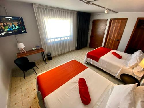 a hotel room with two beds with red pillows at Hotel El Pedregal in Matehuala