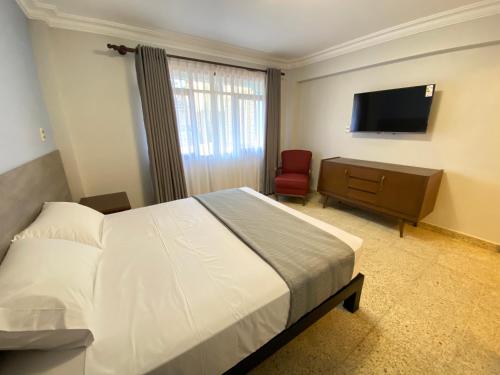 Izza Hotel في كوتشابامبا: غرفة نوم بسرير وتلفزيون بشاشة مسطحة