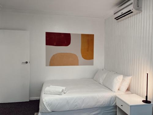 a white bedroom with a bed and a painting on the wall at Gladstone Gem 6 - Suva CBD 2bdrm Apts in Suva