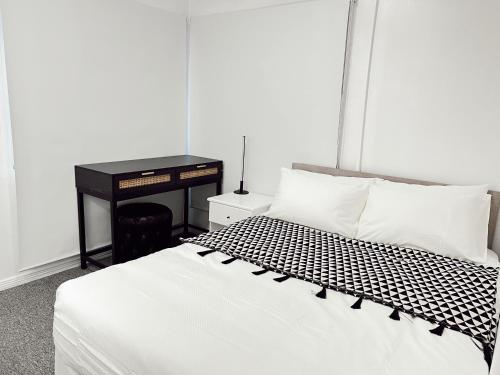 a bedroom with a white bed with a desk and a bed sidx sidx at Gladstone Gem 6 - Suva CBD 2 Bedroom Apartment in Suva