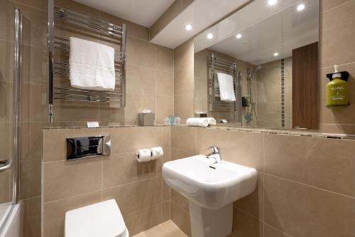 a bathroom with a sink and a toilet and a mirror at Holiday Inn Newcastle Gosforth Park by IHG in Newcastle upon Tyne