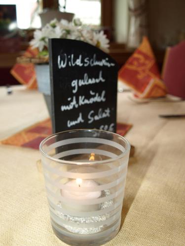 a candle in a glass next to a chalkboard at Gasthof zur Sonne in Jettingen-Scheppach