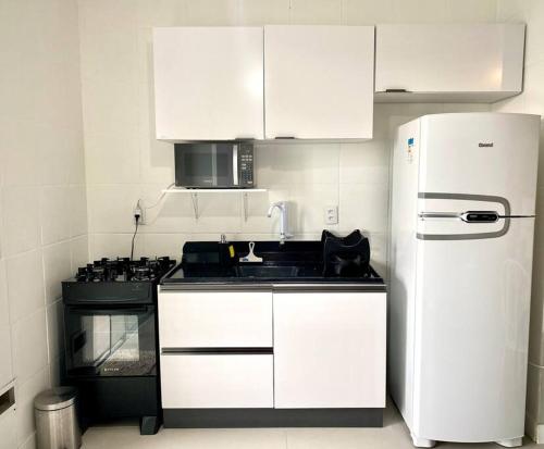 uma cozinha com armários brancos e um frigorífico branco em Canas303 - Apartamento próximo a praia na avenida principal em Florianópolis
