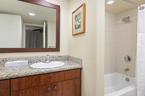 a bathroom with a sink and a tub and a mirror at Aston Islander On The Beach in Kapaa