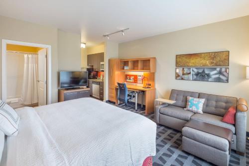 a bedroom with a bed and a couch and a kitchen at TownePlace Suites by Marriott Portland Vancouver in Evergreen