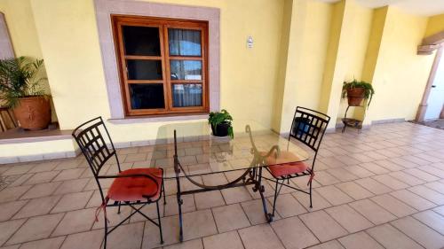 une table en verre avec deux chaises et une fenêtre dans l'établissement Hotel Morada de los Angeles, à Calera Víctor Rosales