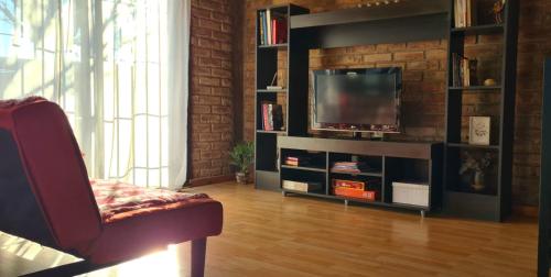 a living room with a television and a brick wall at Departamento completo in Ciudad Lujan de Cuyo