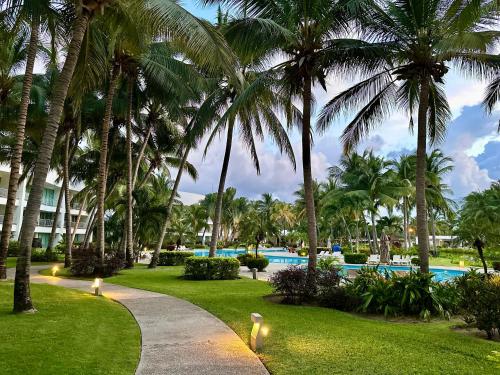a resort with a swimming pool and palm trees at Casa del Sol Lujoso Departamento en Acapulco in Acapulco