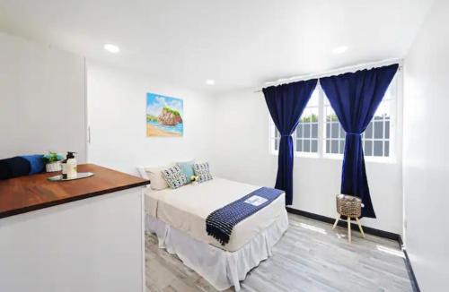 a bedroom with a bed with blue curtains and a window at The Rise South Coast Rental by On Point Property Management in Christ Church