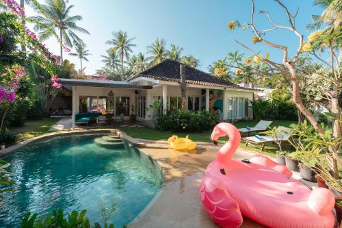 a pool with two pink flamingos in front of a house at Secret Haven Cozy 3 Bedroom Private Pool Villa in Gili Trawangan