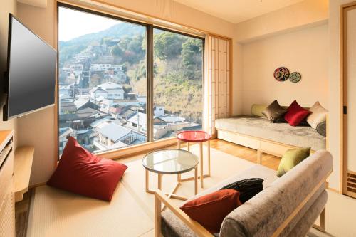 a living room with a couch and a large window at Kotohira Grand Hotel Sakuranosho in Kotohira