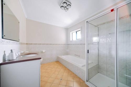 a white bathroom with a shower and a bath tub at Waterfront Townhouse - One in Port Lincoln
