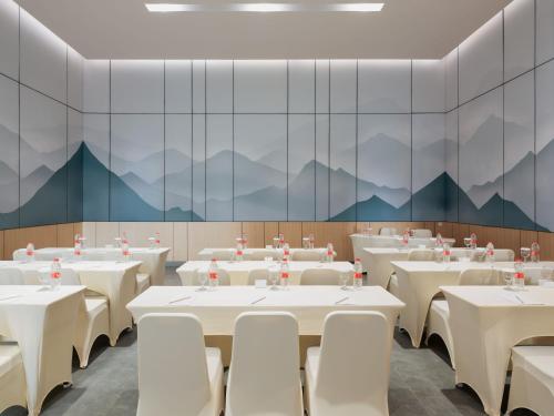 a dining room with tables and chairs and mountains on the wall at Hotel Santika PasirKaliki in Bandung