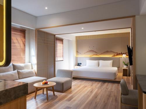a bedroom with a bed and a living room at Hotel Santika PasirKaliki in Bandung