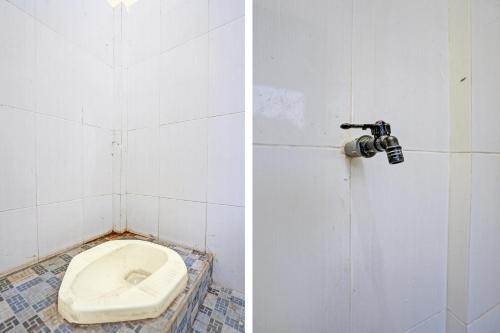 een badkamer met een toilet in een betegelde kamer bij SPOT ON 92799 Tanjung Indah Homestay Syariah in Banyuwangi