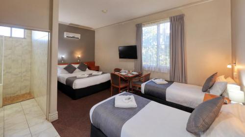 een hotelkamer met 2 bedden en een tafel bij Silver Haven Motor Inn in Broken Hill