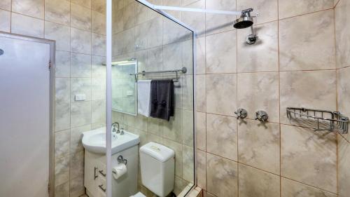 a bathroom with a shower with a toilet and a sink at Silver Haven Motor Inn in Broken Hill