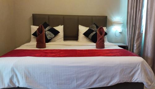 a bedroom with a large bed with red pillows at Destini Akef Villa in Pantai Cenang