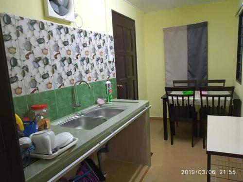 eine Küche mit einer Spüle und einer Arbeitsplatte in der Unterkunft La' Homestay in Kota Bharu