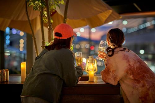 dos personas sentadas en una mesa con copas de vino en Daiwa Roynet Hotel Kyoto Terrace Hachijo PREMIER - former Daiwa Roynet Hotel Kyoto Terrace Hachijohigashiguchi, en Kioto