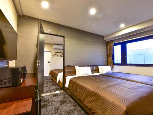 a hotel room with two beds and a television at HOTEL LiVEMAX Fukuoka Tenjin West in Fukuoka