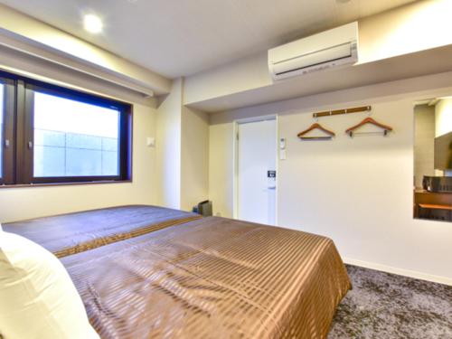 a bedroom with a large bed and a window at HOTEL LiVEMAX Fukuoka Tenjin West in Fukuoka