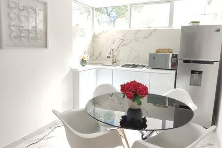 a kitchen with a glass table with a vase of red flowers at Orozco MaiaHome-POLANCO 1BR close to Antara in Mexico City